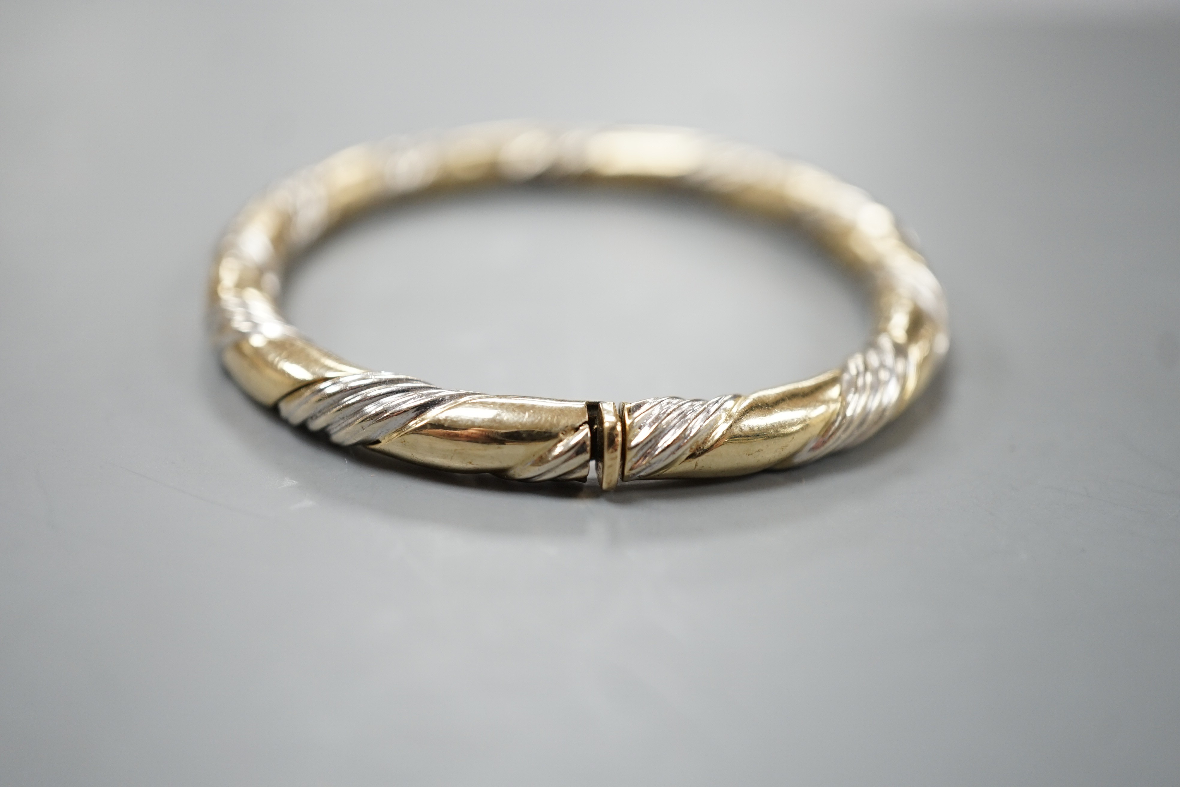 A modern two colour 9ct gold hinged bangle, interior diameter 58mm, 18.7 grams.